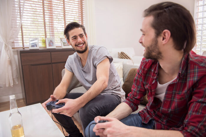 Two men playing video games in living room with psychopath theme