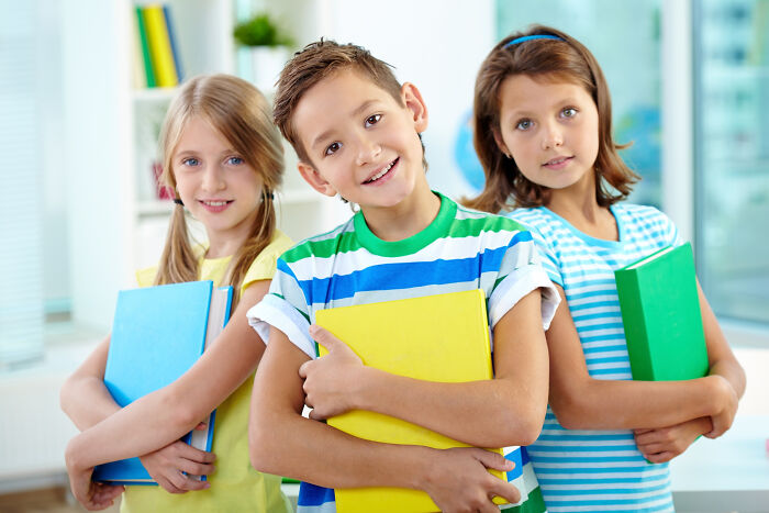 Smiling kids holding books representing awareness about psychopath traits