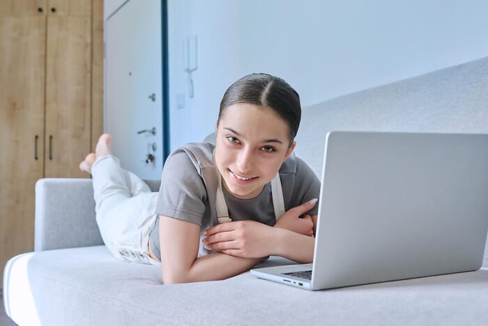 Young woman lying on couch with laptop showing relaxed behavior
