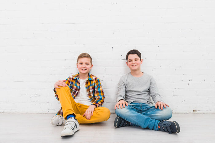 Two boys sitting on floor smiling showing normal behavior comparison