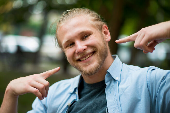 Smiling man pointing at himself with confident psychopath expression