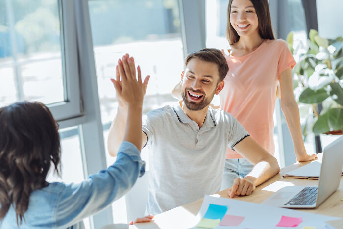 Group high-fiving at work with happy faces showing social interaction