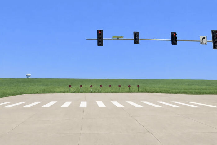 Traffic lights over an empty rural road with a clear horizon create an unsettling liminal space. The scene descends into the abyss.