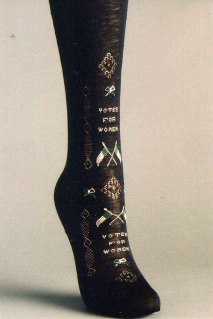 A dark sock with Votes for Women text and flag embroidery, an interesting object that is still intact.