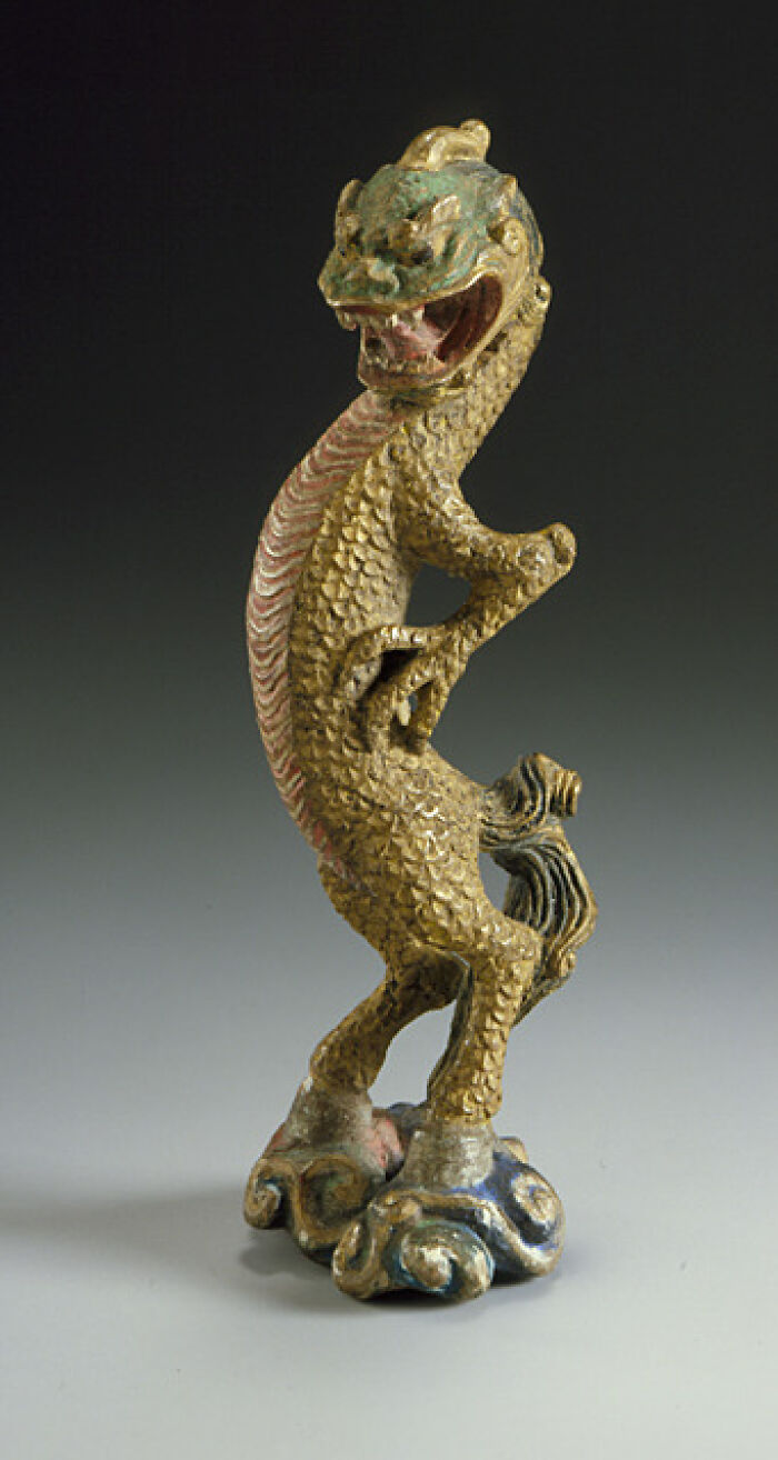 A detailed golden dragon figurine with a green head, an interesting object that is still intact after all these years.