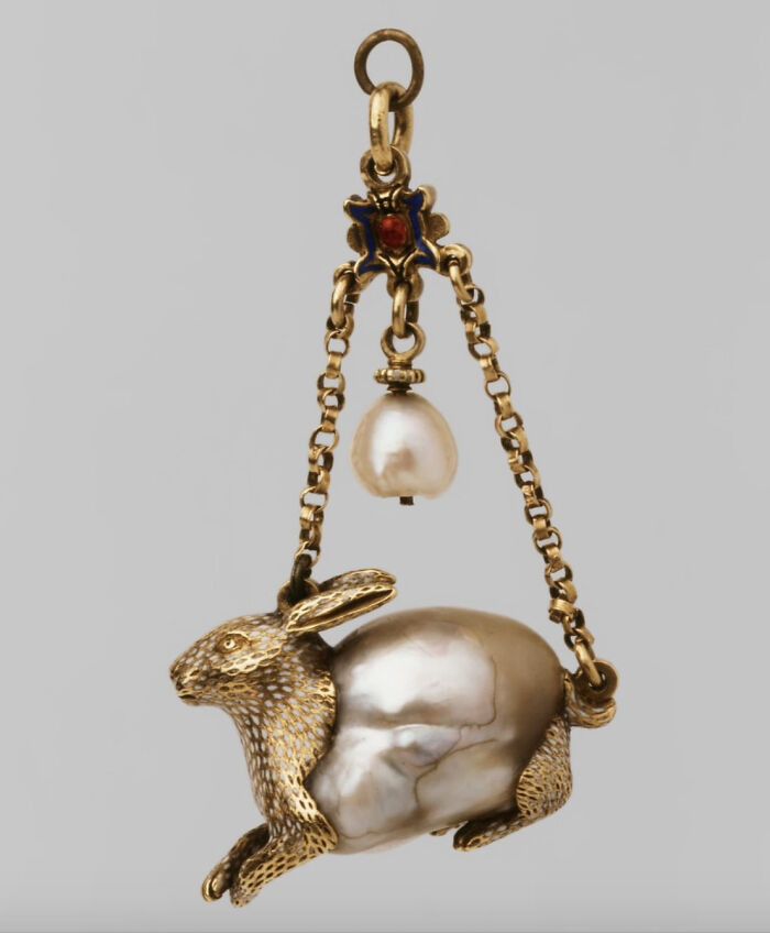 A gold rabbit pendant with a large pearl body, a delicate and intact piece of jewelry.