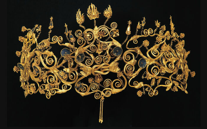 An ornate golden crown with intricate designs and blue accents, an interesting object that is still intact.