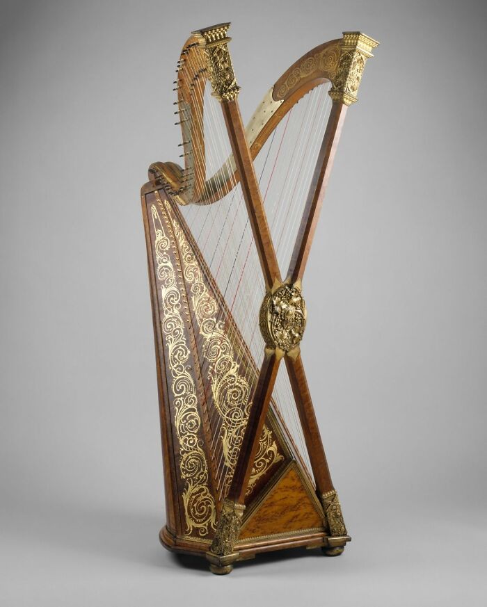 A beautiful and intricate harp, an intact object from many years ago, still retaining its ornate golden details.