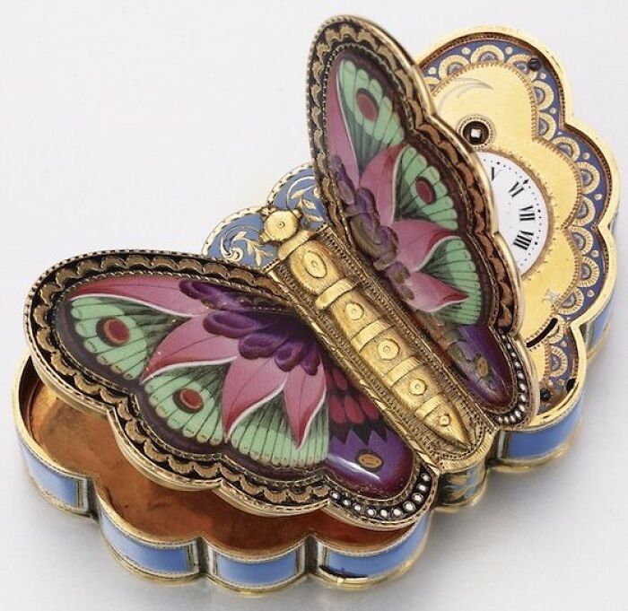 A wonderfully preserved butterfly-shaped clock, an intact object from many years ago, showing delicate craftsmanship and vibrant colors.