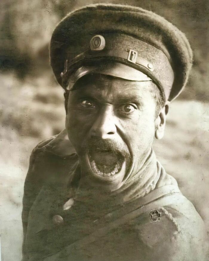 A close-up, intense historical photo of a soldier with a wide-open mouth, shouting.