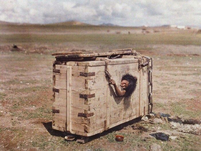 A person imprisoned in a wooden box on a barren plain, a grim example of interesting historical photos.