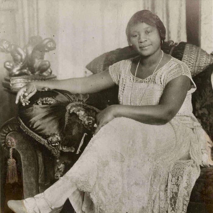 A woman in a white dress and beads poses for a historical photo, showcasing rare and interesting historical photos.