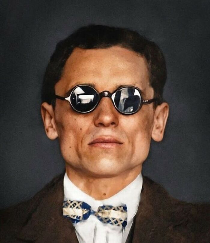 A man with slicked-back hair, a bow tie, and small, round dark sunglasses, a striking historical photo.
