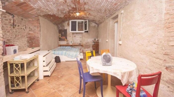 A room with exposed brick walls and ceiling, a cramped living space for an unhinged real estate listing.