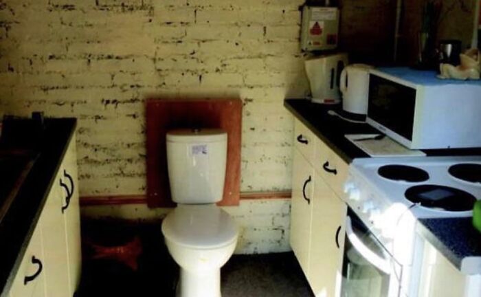 A toilet installed in a kitchen next to a stove and microwave, among unhinged real estate listings.