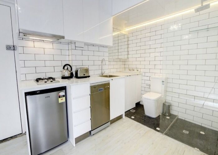 A small kitchen with a toilet integrated into the corner, an unhinged real estate listing.