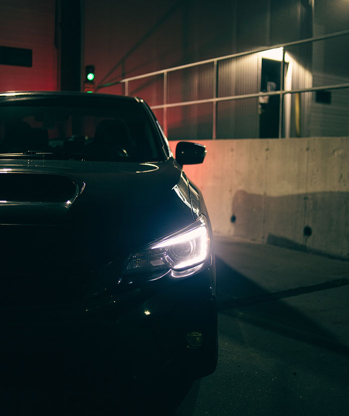 A dark car with headlights on in a dimly lit setting, signaling something was seriously wrong.