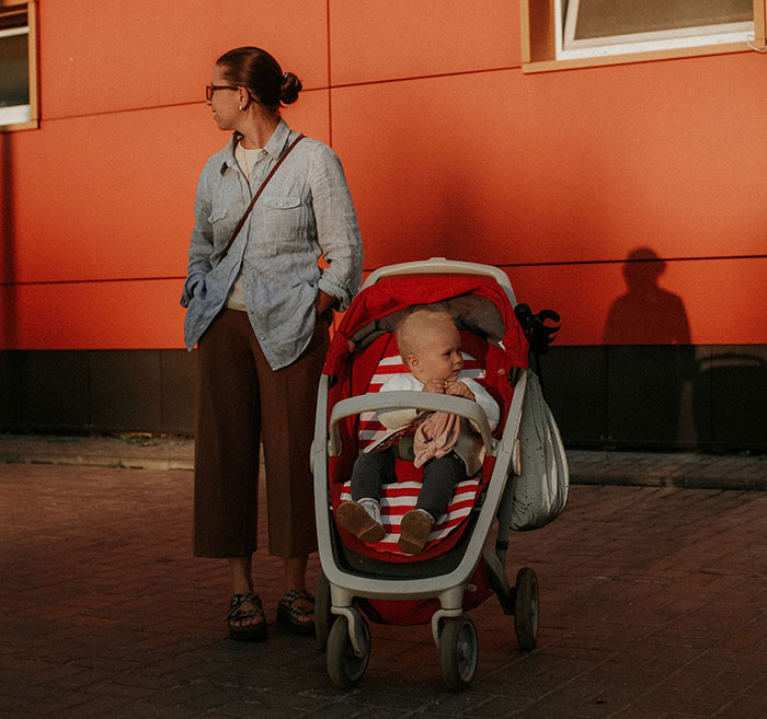 A woman standing next to a baby in a red stroller, reflecting true crime fans realizing something was seriously wrong.