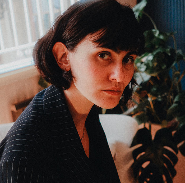 A woman with short dark hair in a pinstripe blazer looks intently, embodying true crime fans realizing something wrong.