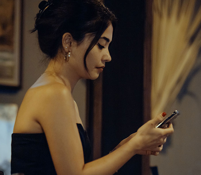 A woman looking at her phone, capturing true crime fans realizing something was seriously wrong.