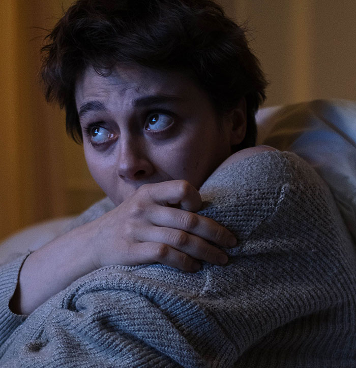 A scared woman looks up, clutching her arm, realizing something was seriously wrong.