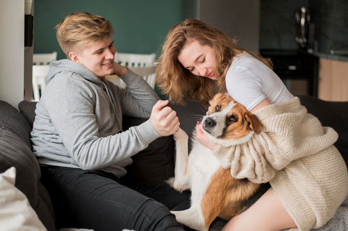 Couple sitting on couch with a dog bonding in a cozy home setting Couple sitting on couch with a dog bonding in a cozy home setting