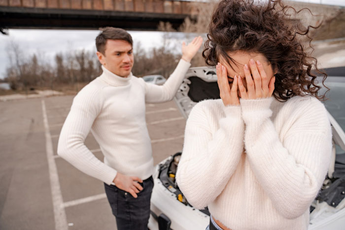 A man gestures in frustration as his fiancée covers her face, depicting a couple after a concert incident. A man gestures in frustration as his fiancée covers her face, depicting a couple after a concert incident.