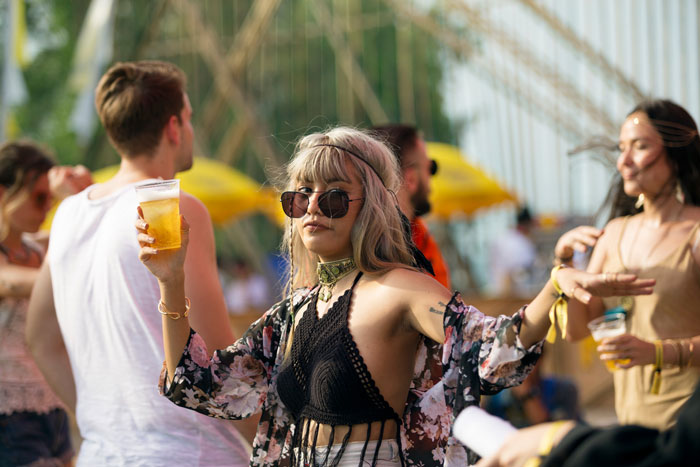 A woman holding a drink at a concert, where a man wants to go home after fainting. A woman holding a drink at a concert, where a man wants to go home after fainting.
