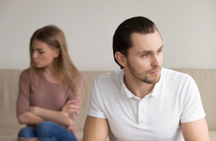 Couple sitting apart looking upset after learning school bully connection Couple sitting apart looking upset after learning school bully connection