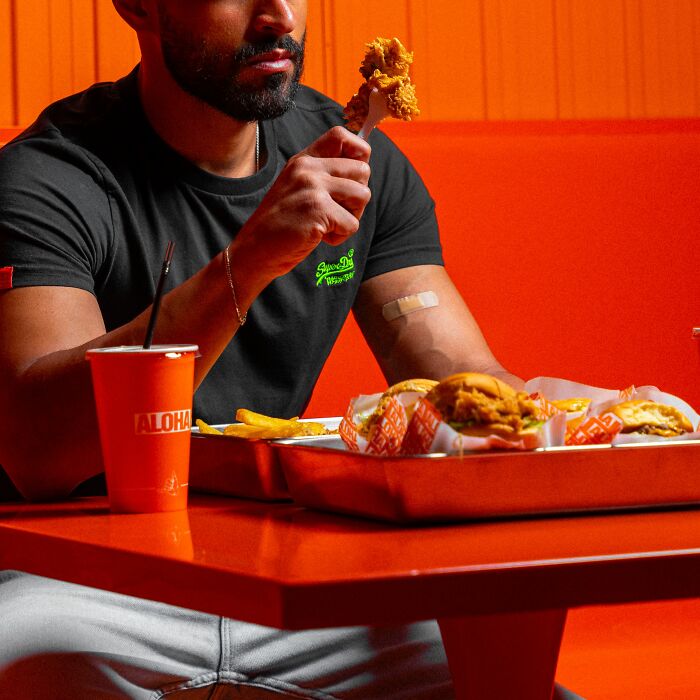 Man eating fried chicken at restaurant with meal tray and drink