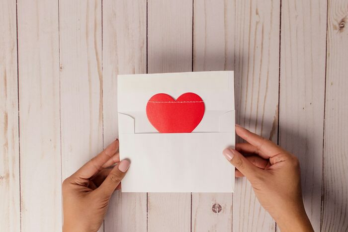 Hands holding an envelope with a red heart, symbolizing diverse and unusual jobs people somehow managed to get hired for.