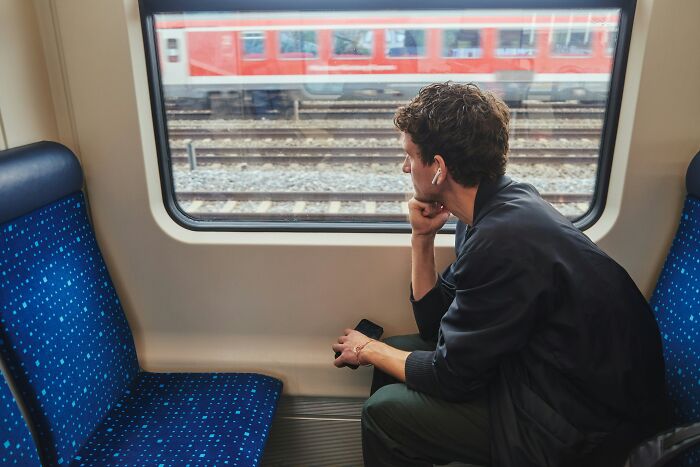 Man looking out train window reflecting on moments of unprompted generosity