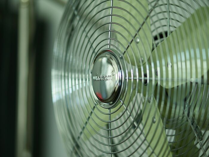 A close-up of a metal fan, a silly solution for keeping cool.