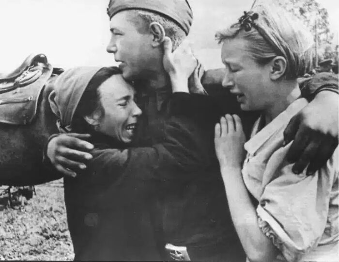 A black and white historical photo captures a soldier embracing two crying women, an impossible to explain moment of raw emotion.