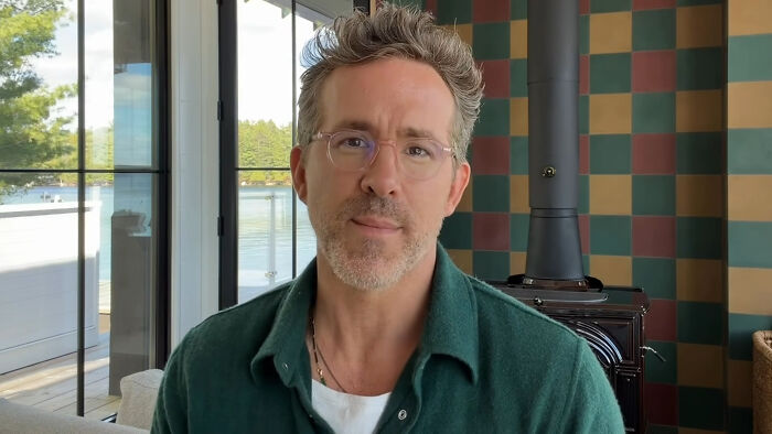 Deadpool star Ryan Reynolds, wearing glasses, speaking on screen.