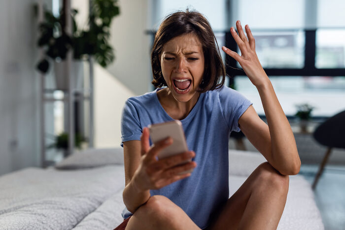 Frustrated woman reading angry message on phone petty revenge