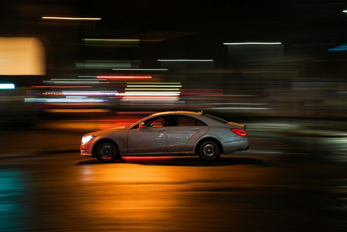 Silver car speeding on wet road at night with motion blur petty revenge stories