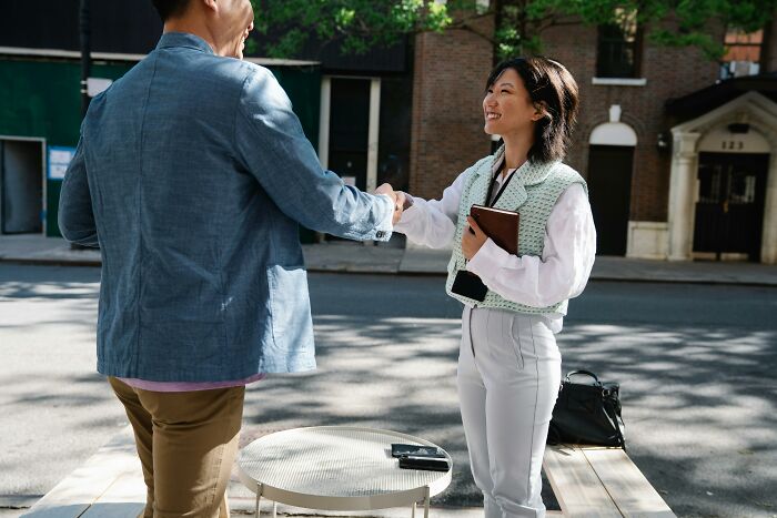 Man and woman shaking hands outdoors in casual business meeting petty revenge stories