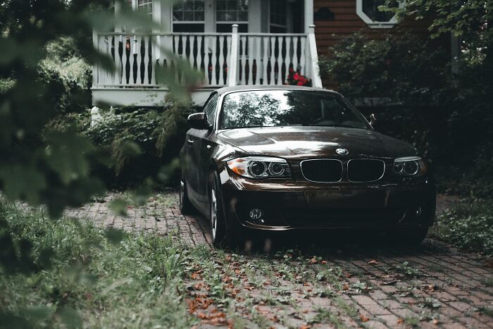 Parked BMW on driveway with autumn leaves referencing petty revenge stories