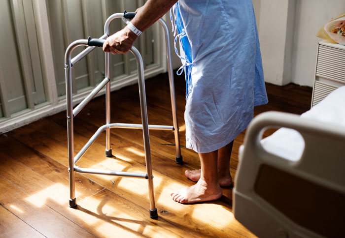 A person using a walker, illustrating the mobility needs of a disabled teen who requires an elevator key for access.
