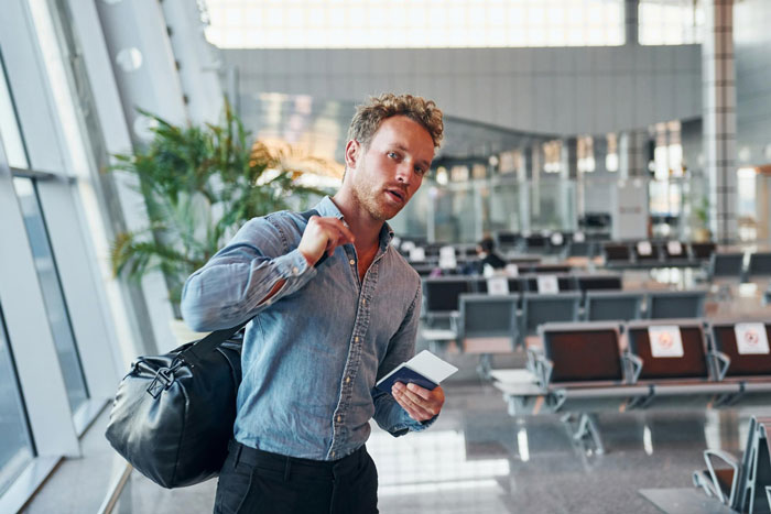 Man at airport holding passport and duffel bag ready for flight Man at airport holding passport and duffel bag ready for flight