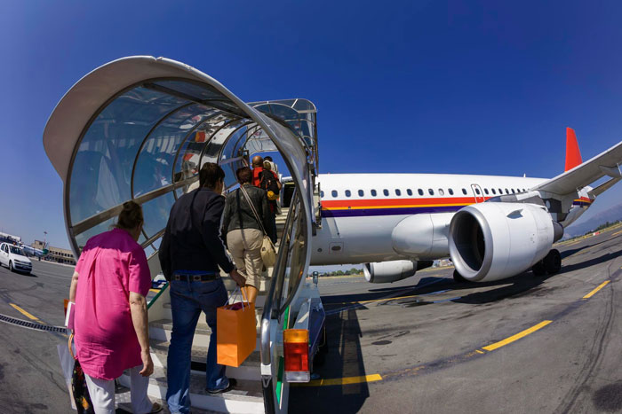 Passengers boarding a commercial airplane via covered stairway on airport tarmac Passengers boarding a commercial airplane via covered stairway on airport tarmac