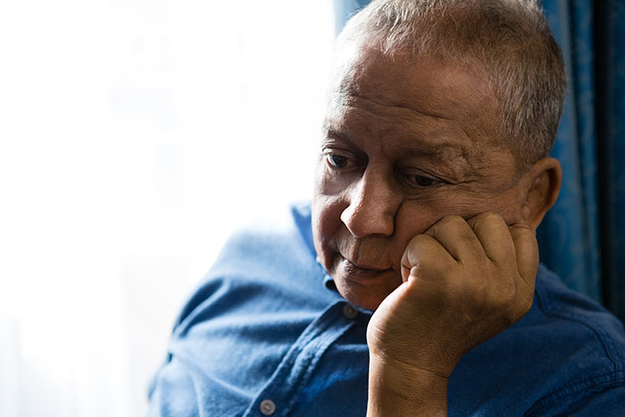 An older man with a pensive expression, reflecting on secrets people keep to themselves about others.
