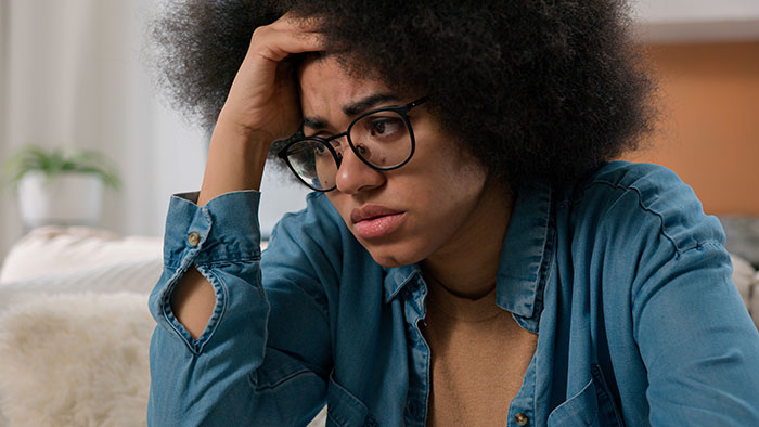 A worried woman holding her head, symbolizing the burden of secrets people keep to themselves.