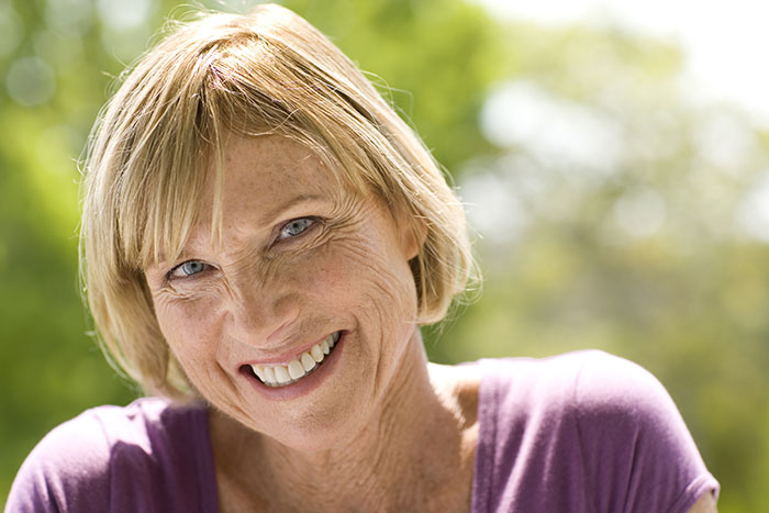 A smiling woman, suggesting secrets people keep to themselves that affect their lives.