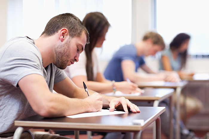 Students writing in a classroom, representing the internal world of secrets people keep about others.