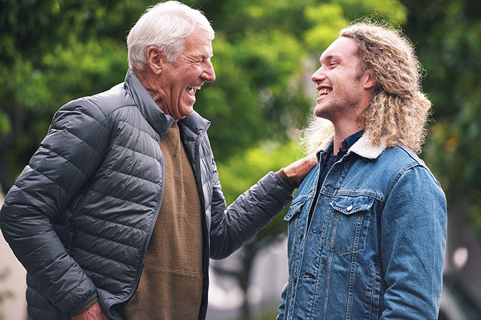 An older man and a younger man laughing together, showing how secrets people keep can impact relationships.