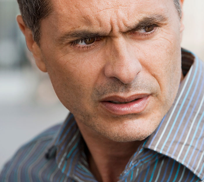 A man with a furrowed brow, looking concerned, representing the secrets people keep to themselves about others.