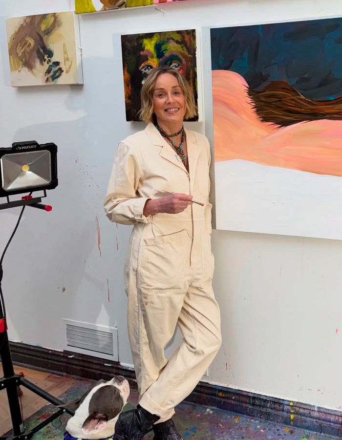 Sharon Stone painting in art studio wearing cream jumpsuit