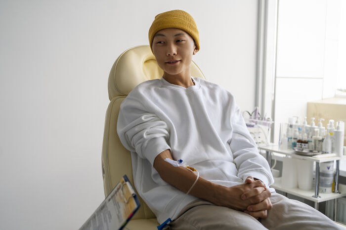 A young man in a yellow beanie sitting with an IV in his arm, facing an awkward situation.